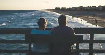 man and woman sitting on bench in front of beach