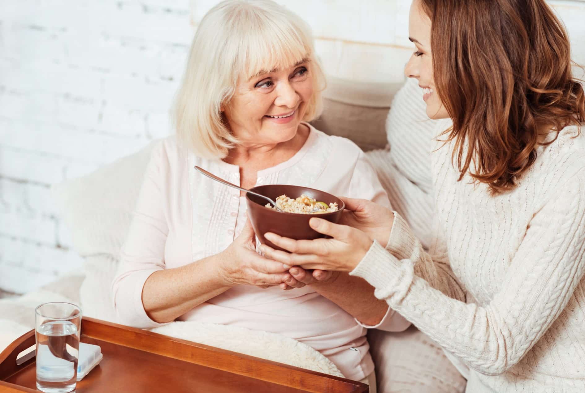 Une femme qui sert une petit déjeuner à une personne agée